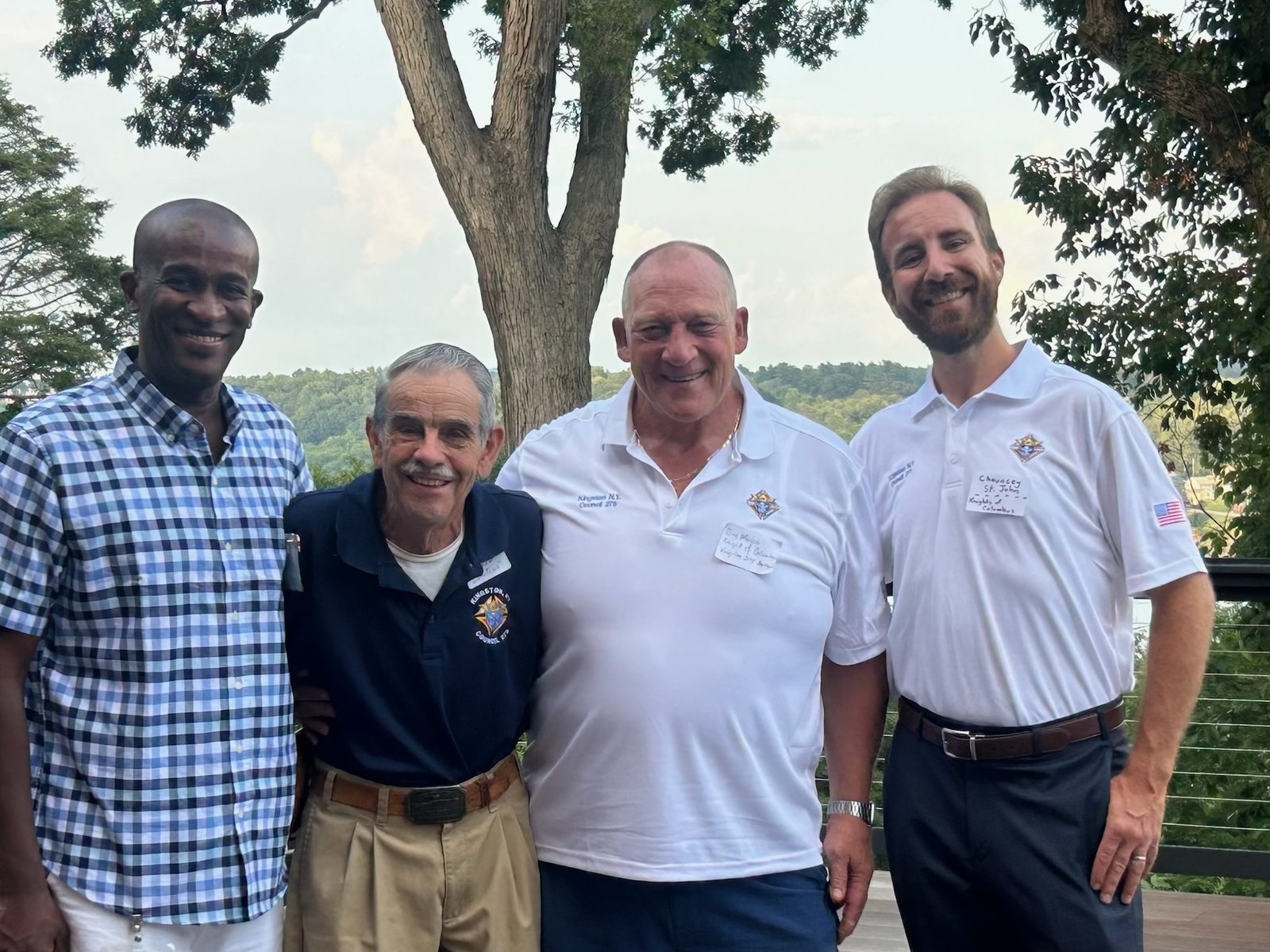 Four members of Kingston Council 275 standing together outdoors with the Hudson Valley behind them