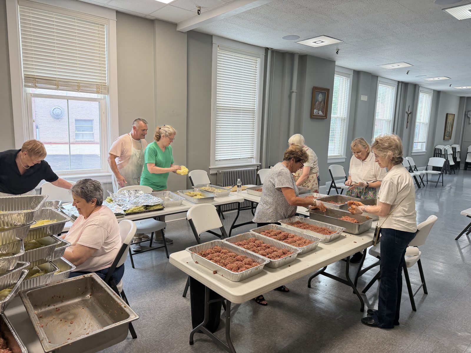 Volunteers assembling trays of food on long tables in the parish hall
